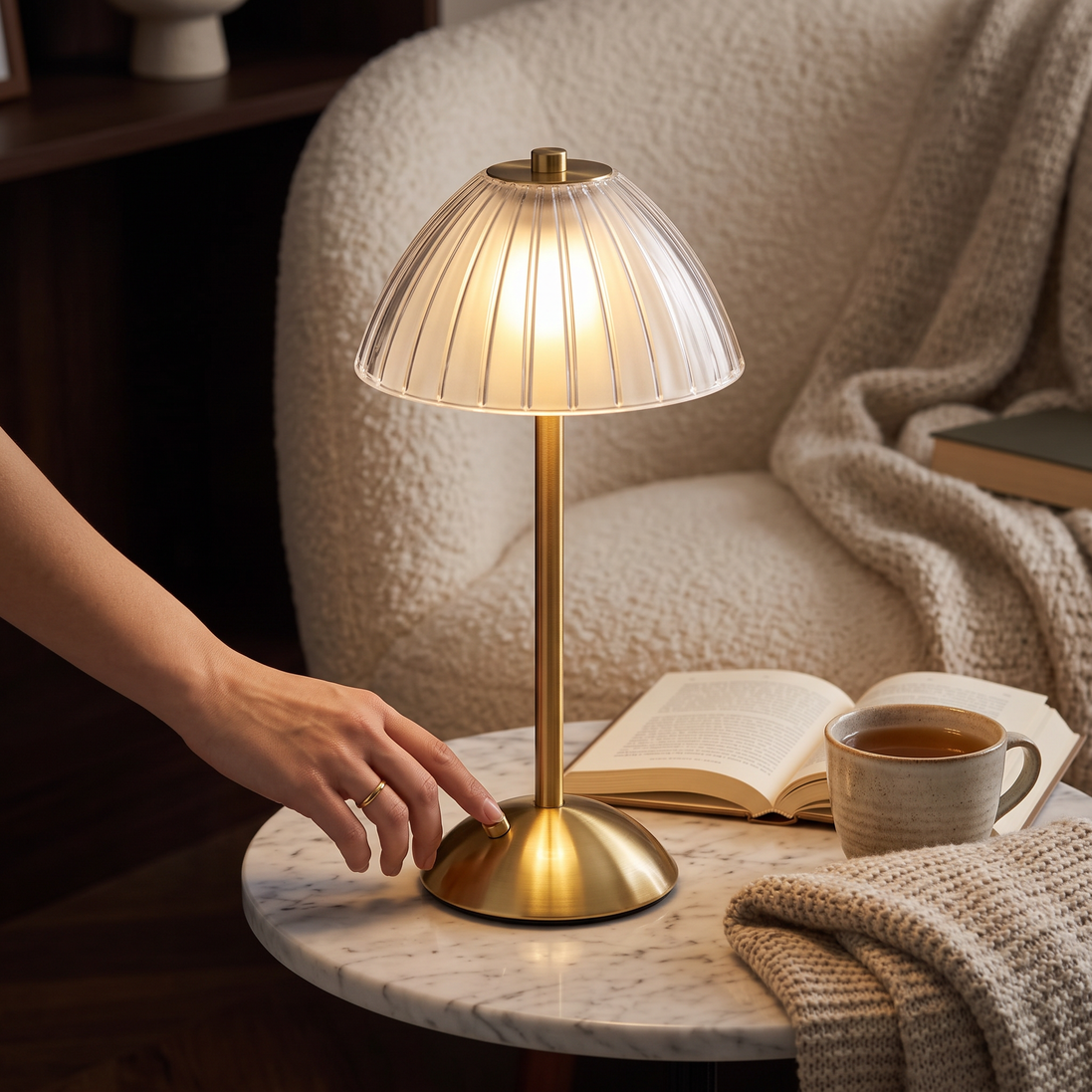 Hand reaching for the Golden Touch Table Lamp in a reading nook