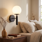 Glass Globe Wall Sconce in black by a bed