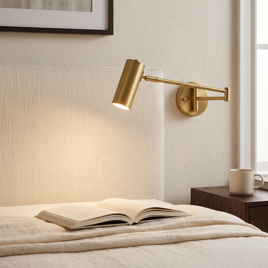 Arvilo Swing-Arm Wall Light in brass above a bed