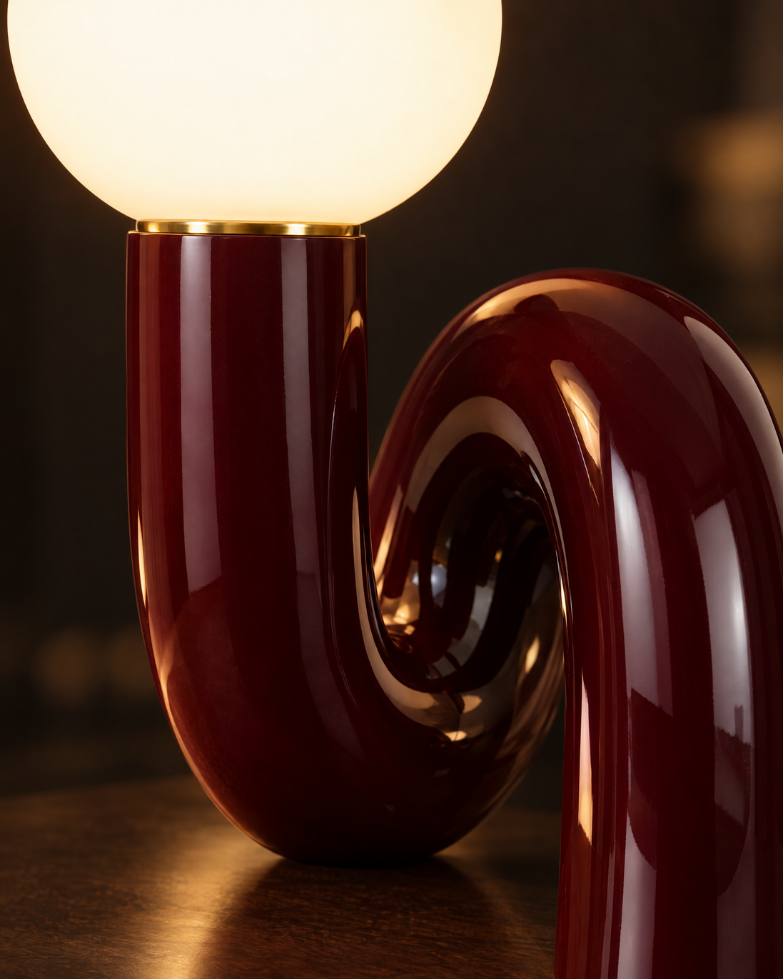 Close-up of the glowing frosted glass globe and glossy dark red curve