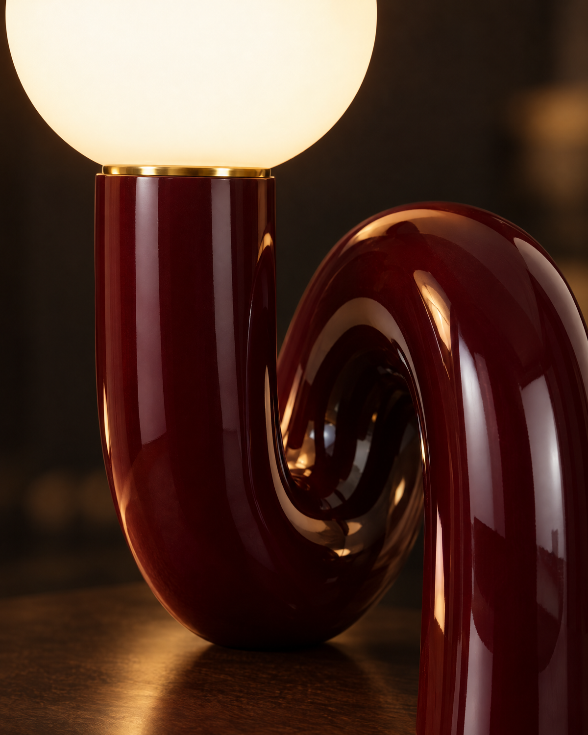 Close-up of the glowing frosted glass globe and glossy dark red curve